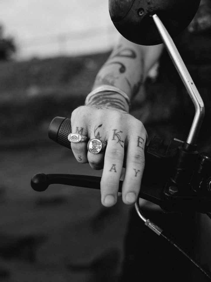 grayscale photo of person with rings and tattoos